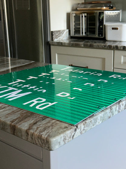 Green street sign with white text leaning against a kitchen counter.